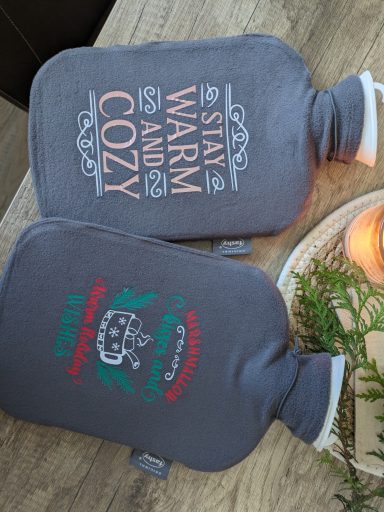 Zwei Wärmflaschen mit den Aufschriften "Stay Warm" und "Cozy".